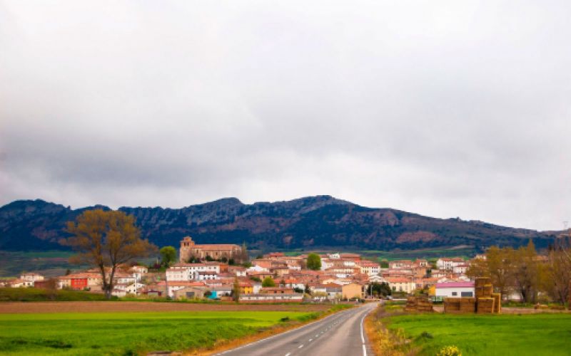 Vista de pueblo desde la carretera con los montes Obarenes de fondo