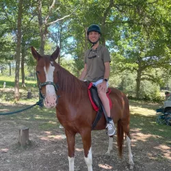 Persona montando un caballo con apoyo de dos guías.