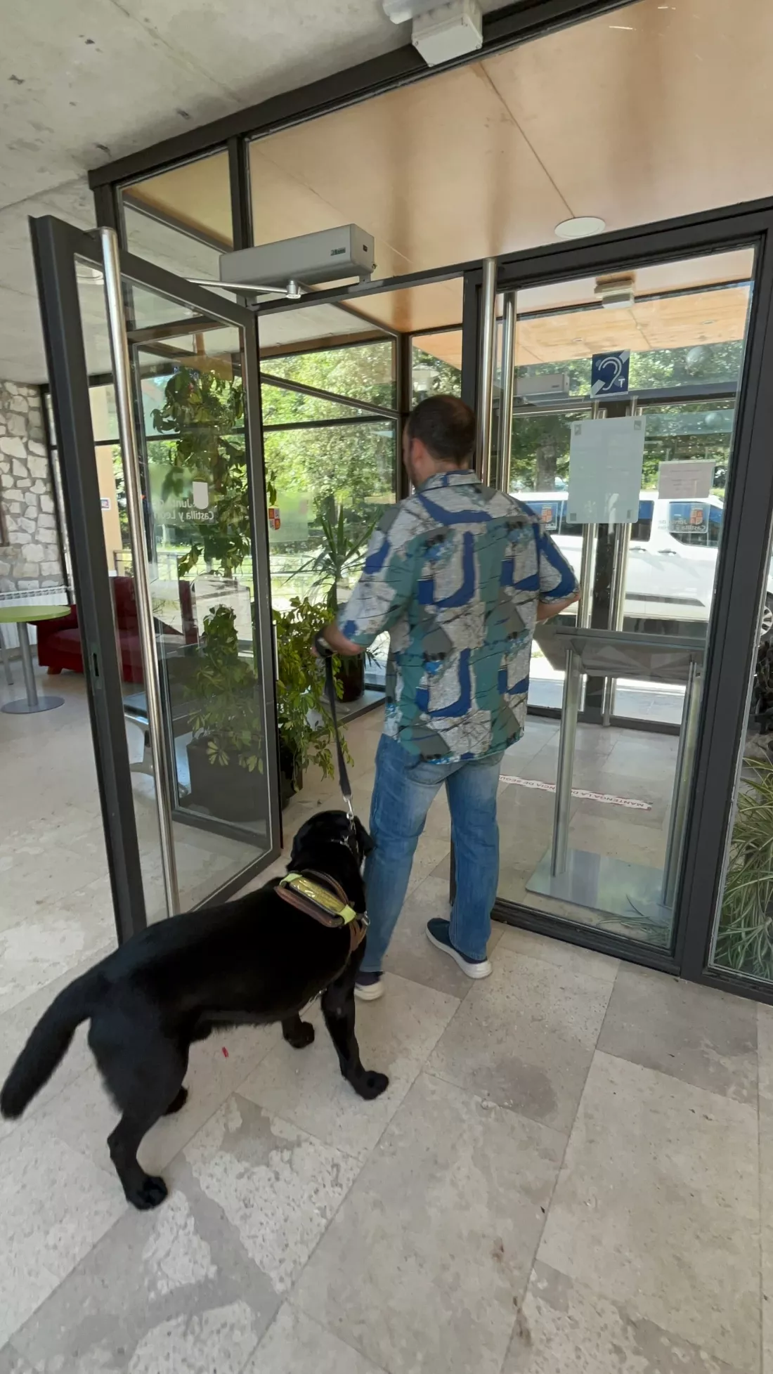 Hombre con perro guía entra a un edificio accesible.
