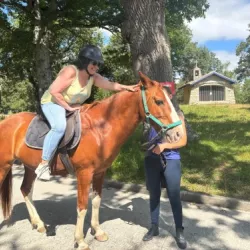 Mujer montada en un caballo frente a una pequeña ermita