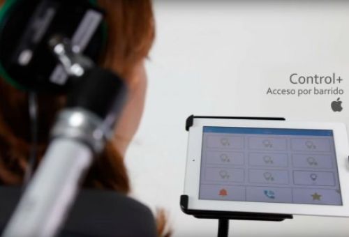 Persona usando auriculares especiales y una tablet con interfaz de control por barrido, mostrando el logo de Apple y el texto "Control+ Acceso por barrido"