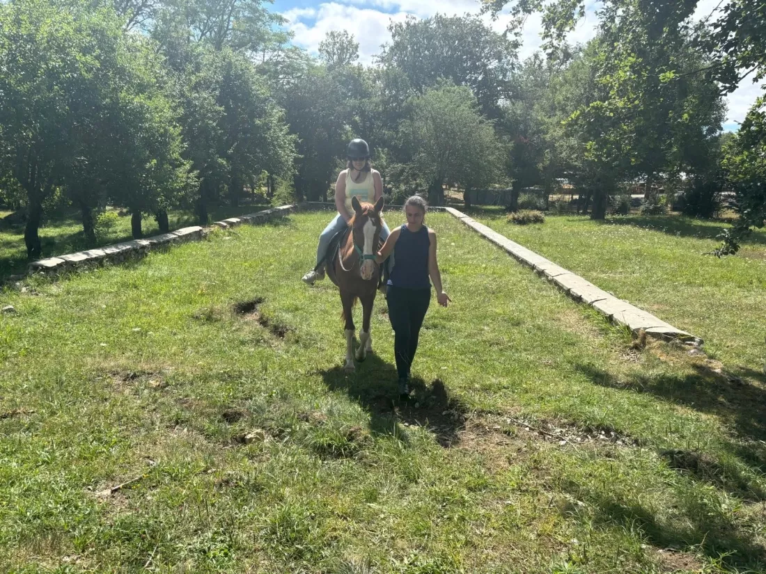 Persona con discapacidad acariciando un caballo acompañado de un guía.