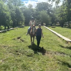 Persona con discapacidad acariciando un caballo acompañado de un guía.