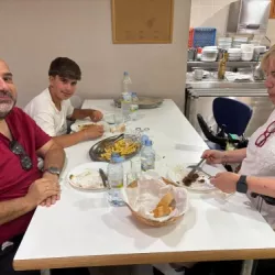 Tres personas sentadas comiendo, una de ellas en silla de ruedas, en un comedor accesible.