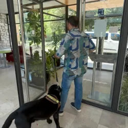 Hombre con perro guía entra a un edificio accesible.