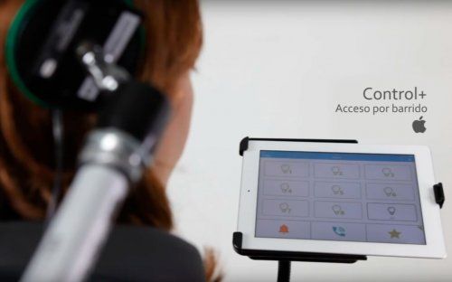 Persona usando auriculares especiales y una tablet con interfaz de control por barrido, mostrando el logo de Apple y el texto "Control+ Acceso por barrido"