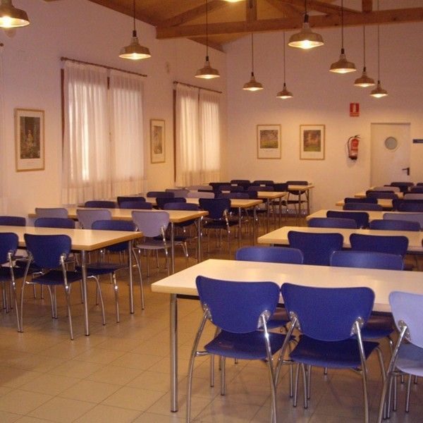 Amplio comedor junto a la cocina con mesas rectangulares y varias sillas