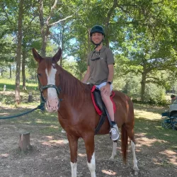 Persona montando un caballo con apoyo de dos guías.