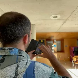 Hombre utiliza su móvil para leer información accesible en el interior del edificio.