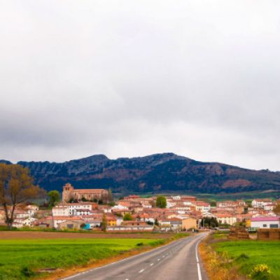 Vista de pueblo desde la carretera con los montes Obarenes de fondo
