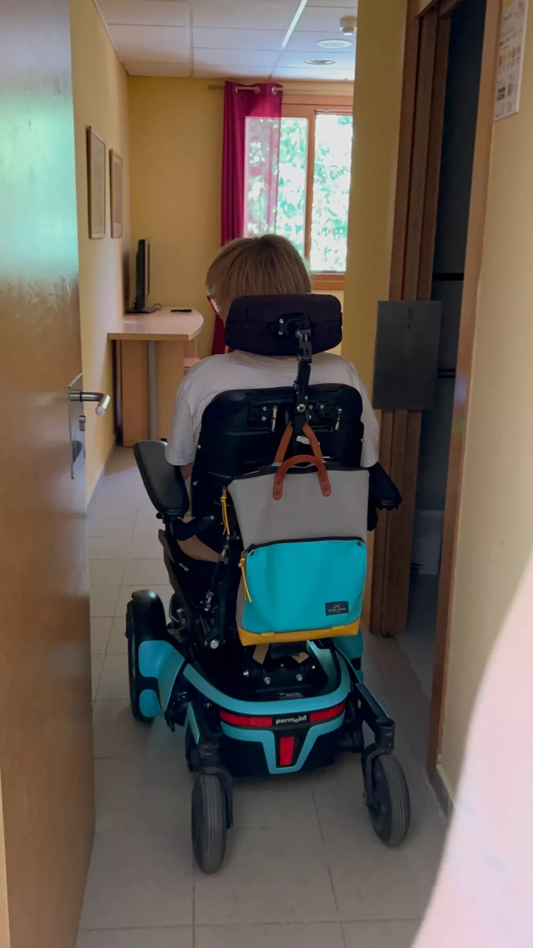 Persona en silla de ruedas eléctrica accede a una habitación adaptada.