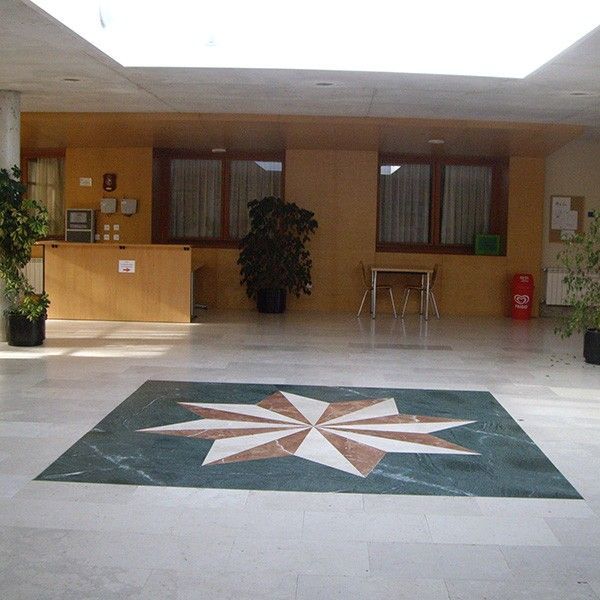 Hall de entrada con mucha iluminación superior e imagen de rosa de los vientos en el suelo