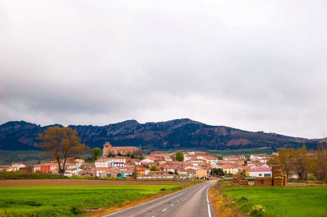 Vista de pueblo desde la carretera con los montes Obarenes de fondo